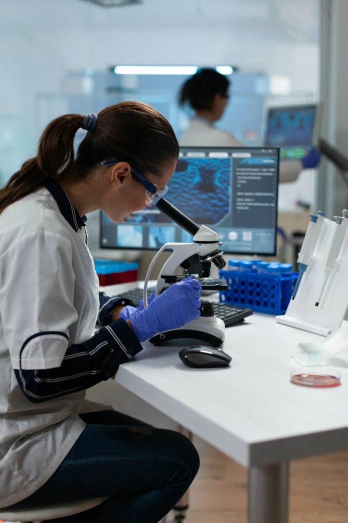 Specialist biologist researcher analyzing biomedical virus sample using medical microscope